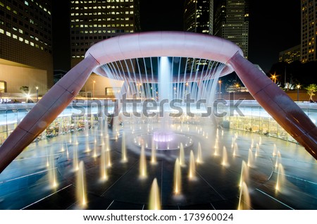 SINGAPORE-JAN 24: Fountain of Wealth with Suntec Towers at dusk on JAN 24,2014 in Singapore. Fountain of wealth is the biggest fountain in Singapore located Suntec Towers, SINGAPORE.