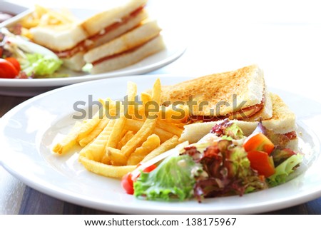 Delicious club sandwich with french fries and salad
