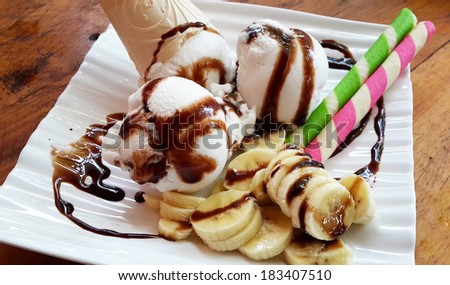 Coconut ice cream with banana in white plate on wood table