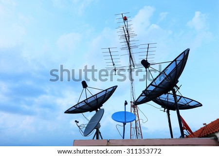 Satellite Dishes and TV antennas on the house roof with a beautiful blue sky