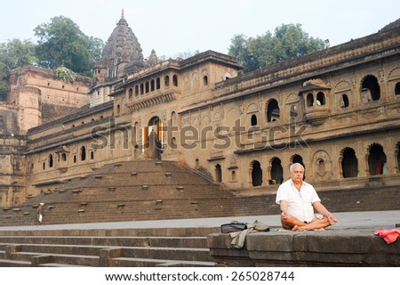 Maheshwar, India - 4 February 2015: Man doing yoga and meditation in front of Maheshwar palace on India