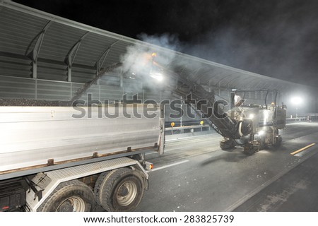 Bissone, Switzerland - 14 September 2007: Workers and vehicles during the road milling of the highway by night at Bissone on Switzerland