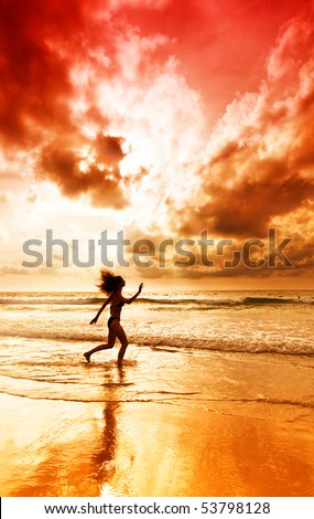 Dancing girl on a tropical beach under the sky at sunset