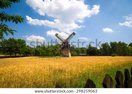 Agricultural summer landscape with old windmill and blue sky
