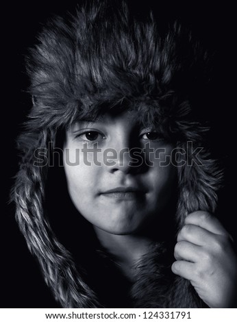 Black-and-white portrait of  boy in  fur cap with ear-flaps