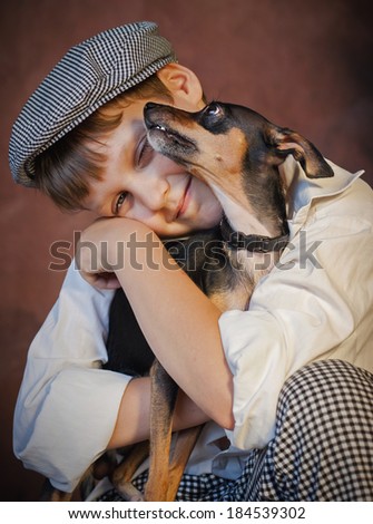Portrait of  boy in plaid pants and cap, with  dog is on  hands