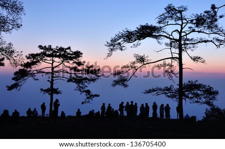 Silhouette of people waiting for sunrise in dawn at Makdook cliff, Thailand.