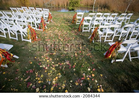 Outside wedding scene with white chairs and leaves in the grass