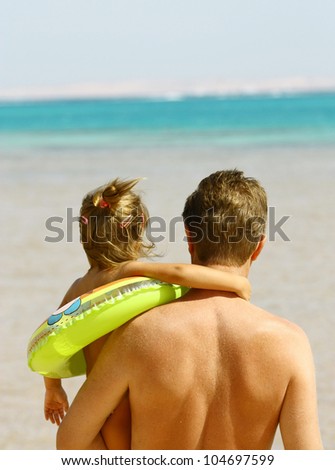 Back view of father and daughter looking to ocean