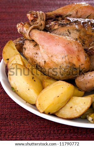 Roasted whole chicken on a plate with fried potato and asparagus