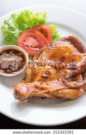 Thai style grilled chicken drumstick with spicy sauce and fresh vegetable on dish