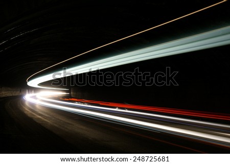 Abstract blue, yellow, white and red rays of light in a car tunnel