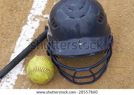 a bat, softball and helmet on the infield