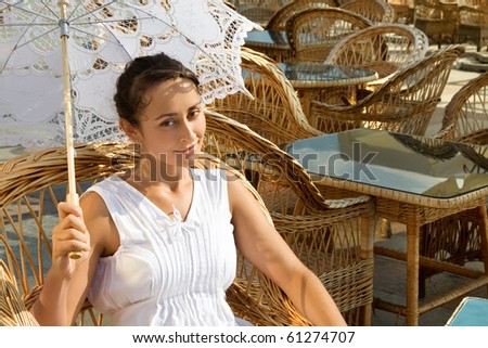 Young attractive lady with sun umbrella sitting in the cafe