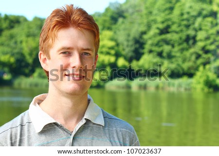 Portrait of a young red haired man over rural landscape