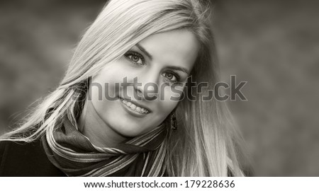 Black and white portrait of a young smiling blond girl with braces
