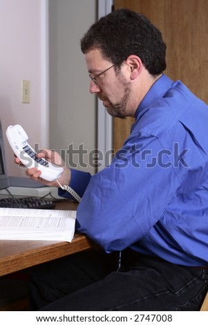 Middle-aged man using the telephone in a home office.