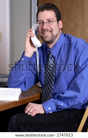 Middle-aged man using the telephone in a home office.
