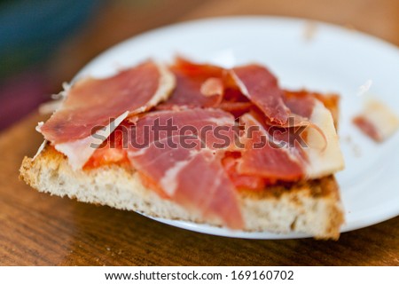 Thinly sliced smoked ham served on freshly baked bread for a delicious lunchtime snack, close up view of the plate and sandwich