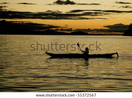 Kayaker paddles among Washington's San Juan Islands at sunset