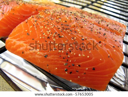 Raw peppered salmon prepped to cook on a grill sheet