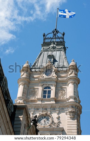 The clock tower of Parliament of Quebec building and Quebec flag.