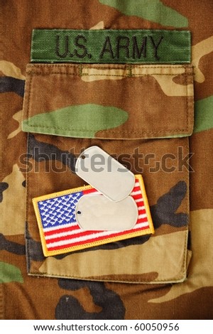 US flag and dog tags on woodland camo pocket background