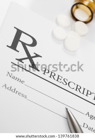 Blank medical prescription, pills and pen on table