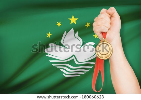 Sportsman holding gold medal with flag on background - Macao Special Administrative Region of the People\'s Republic of China