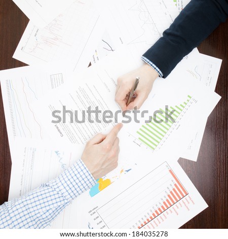 Business men analyzing some business information at the desk - view from the top - 1 to 1 ratio
