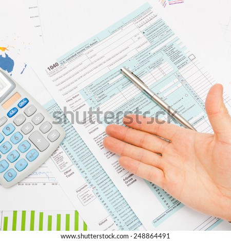 US 1040 Tax Form, calculator, male hand and silver pen - studio shot