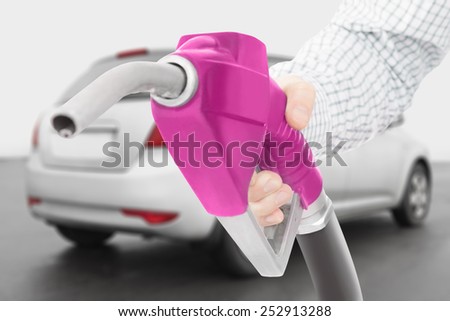 Pink color fuel pump gun in hand with car on background
