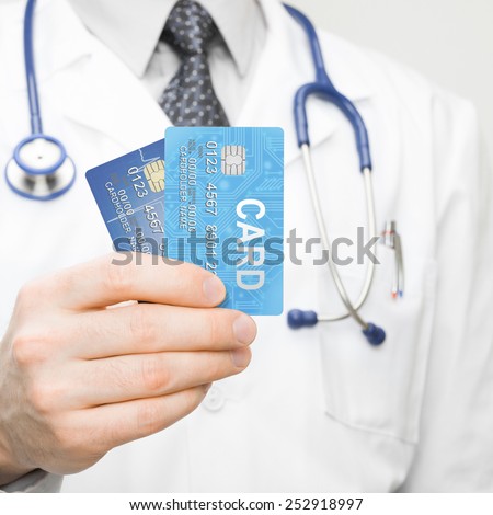 Medical doctor holding two credit cards in his hand - closeup shot