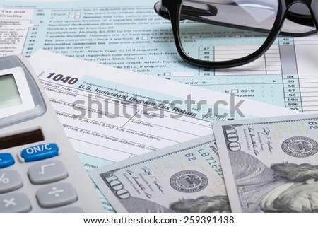 US 1040 Tax Form, calculator, glasses and dollars - studio shot