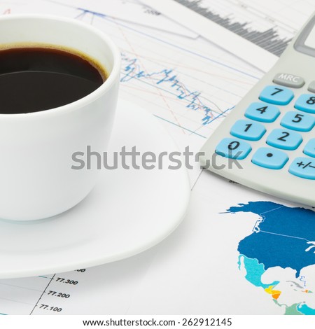Coffee cup and calculator over world map and some financial charts - business concept