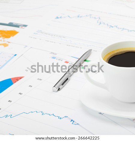 Coffee cup over world map and some financial charts - close up shot