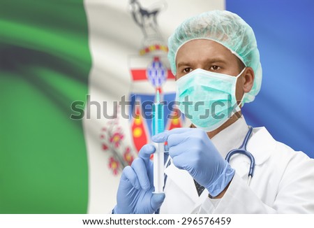 Doctor with syringe in hands and Canadian province flag on background - Yukon
