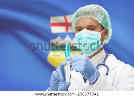 Doctor with syringe in hands and Canadian province flag on background - Alberta
