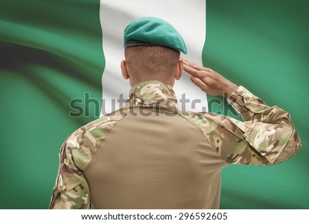 Dark-skinned soldier in hat facing national flag series - Nigeria
