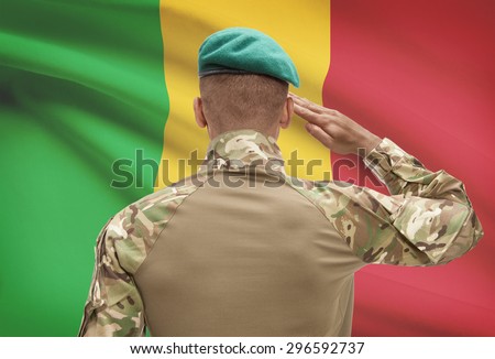 Dark-skinned soldier in hat facing national flag series - Mali