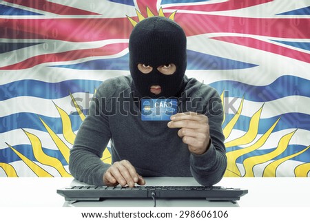 Dark-skinned hacker with credit card and Canadian province flag on background - British Columbia