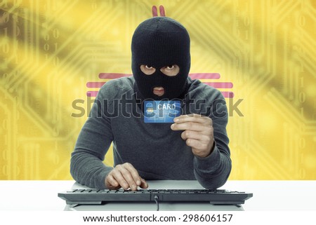 Dark-skinned hacker with credit card and USA states flag on background - New Mexico