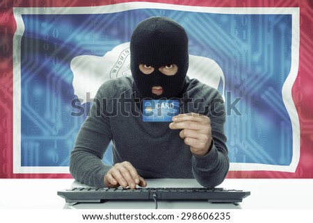 Dark-skinned hacker with credit card and USA states flag on background - Wyoming