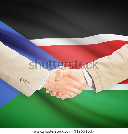 Businessmen shaking hands with flag on background - South Sudan