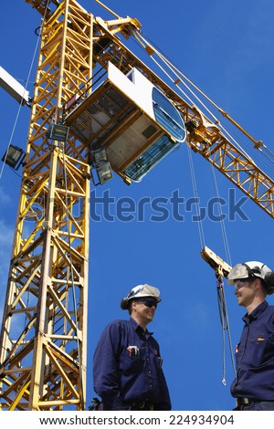 construction workers with tall mobile crane in the background