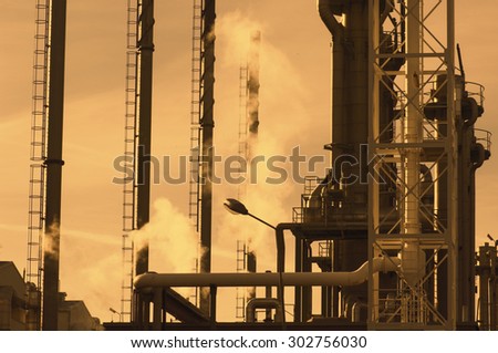 oil industry refinery, pipes and chimneys at sunset