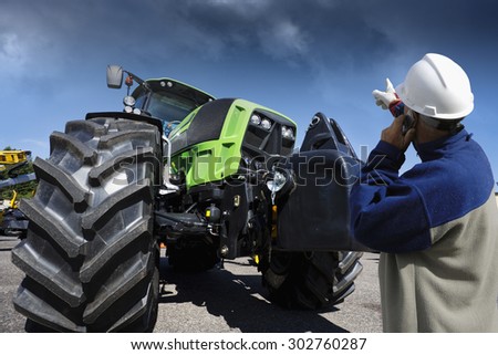 farmer, mechanic pointing at his farming tractor, latest model