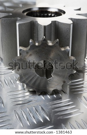 large and smaller cog-wheels against patterned-steel