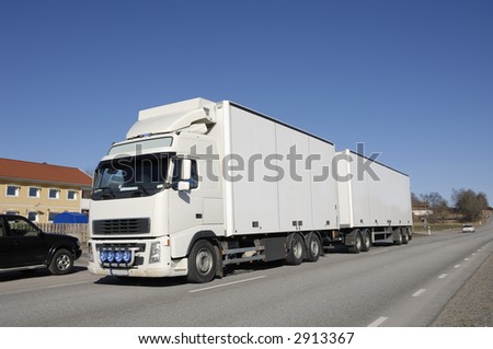 clean white truck driving on country-road, houses and cars