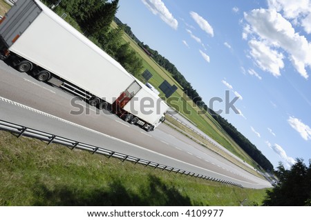 white truck driving on highway surrounded by country-side and in an extreme angle of view